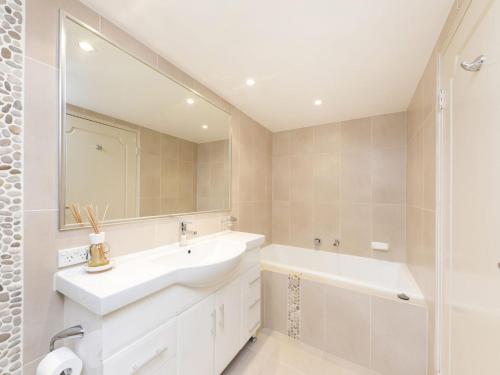 ein Badezimmer mit einem Waschbecken, einer Badewanne und einem Spiegel in der Unterkunft Wallis Court 6 in Forster