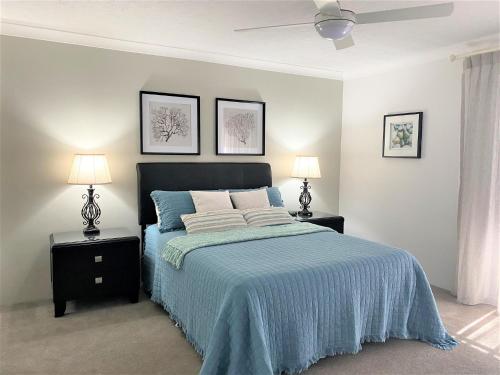 een slaapkamer met een bed met een blauwe deken en 2 lampen bij Wallis Court 6 in Forster