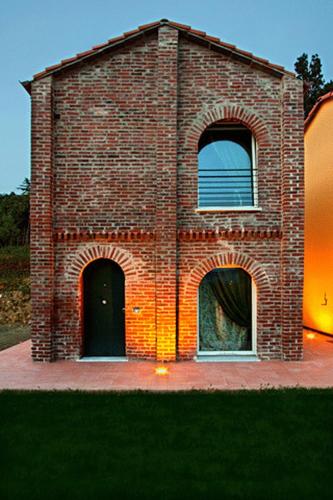 a brick building with two windows on the side at Casali Romei in Sarzana