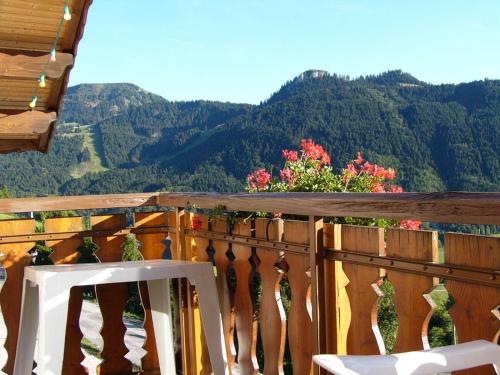 a white chair on a wooden balcony with mountains in the background at Chalet Titlis in Bernex