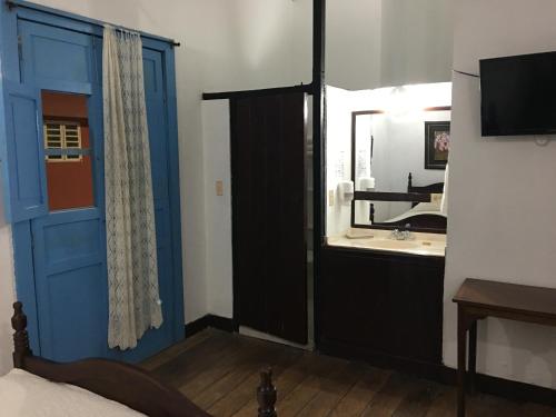 a bedroom with a blue door and a bathroom with a sink at Casa Hotel El Compadre in Filandia