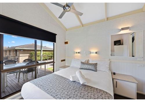 a bedroom with a white bed and a balcony at Discovery Parks - Warrnambool in Warrnambool