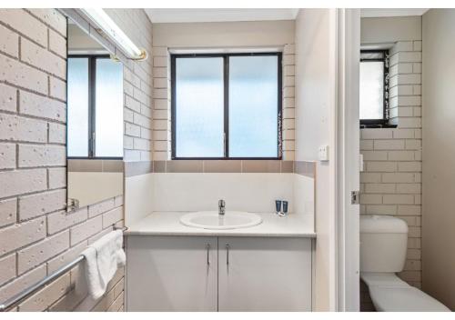 a bathroom with a sink and a brick wall at Discovery Parks - Warrnambool in Warrnambool