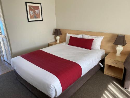 a bedroom with a large bed with a red pillow at Country Gardens Motel in Coonabarabran