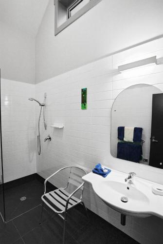 a bathroom with a sink and a mirror and a chair at Taranaki Country Lodge in New Plymouth