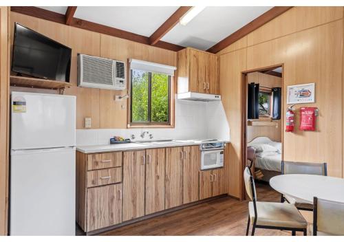 a kitchen with a white refrigerator and a table at Discovery Parks - Warrnambool in Warrnambool