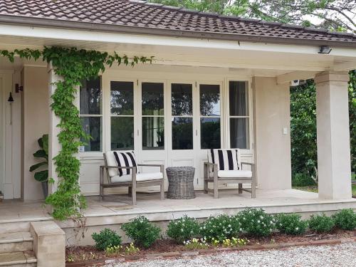 a screened in porch with two chairs and windows at Kirriemuir Burradoo Southern Highlands in Burradoo