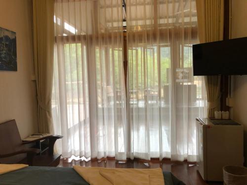 a bedroom with a large window with white curtains at Baan Chan Lay Koh Chang in Ko Chang