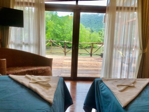 a bedroom with two beds and a large window at Baan Chan Lay Koh Chang in Ko Chang