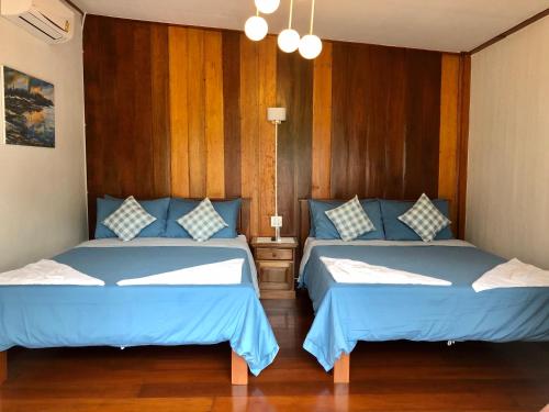a bedroom with two beds with blue sheets and wood walls at Baan Chan Lay Koh Chang in Ko Chang