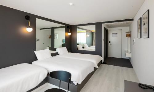 a bedroom with two beds and a mirror at Pampas Hotel Jeju in Jeju