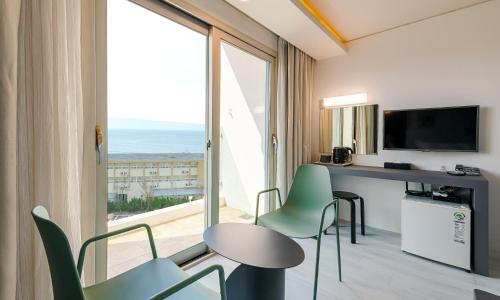 a room with a table and chairs and a large window at Pampas Hotel Jeju in Jeju