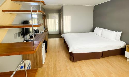 a hotel room with a bed and a desk at Pampas Hotel Jeju in Jeju