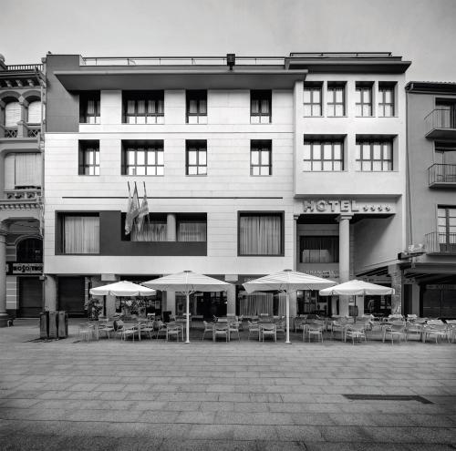 a hotel with tables and umbrellas in front of it at Gran Hotel Ciudad de Barbastro in Barbastro