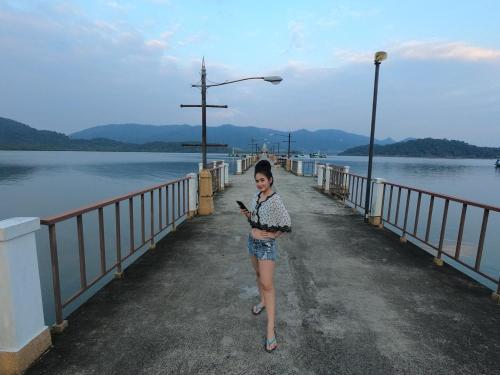 a woman standing on a bridge looking at her cell phone at Baan Chan Lay Koh Chang in Ko Chang