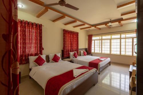 two beds in a room with red curtains at KSTDC Hotel Mayura Shantala Halebeedu in Halebīd