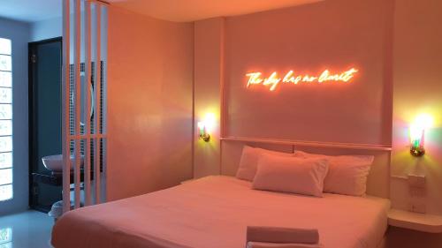 a bedroom with a bed with a neon sign above it at Goodnight Cha Am Minitel in Cha Am
