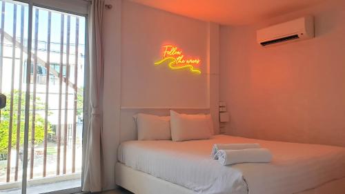七岩的住宿－七岩晚安迷你酒店，卧室配有一张墙上 ⁇ 虹灯标牌的床