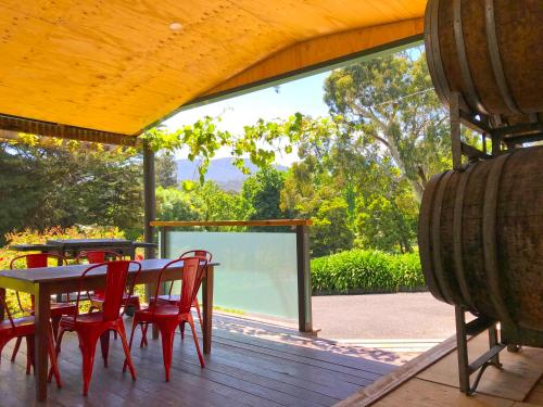 eine Holzterrasse mit einem Tisch und roten Stühlen auf einer Terrasse in der Unterkunft Valley Farm Vineyard Villas in Healesville