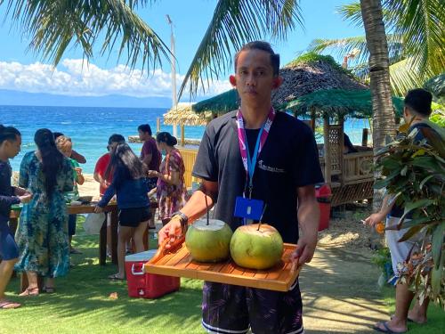 a man holding a cutting board with two coconuts at Rio Beach Resort in Alegria