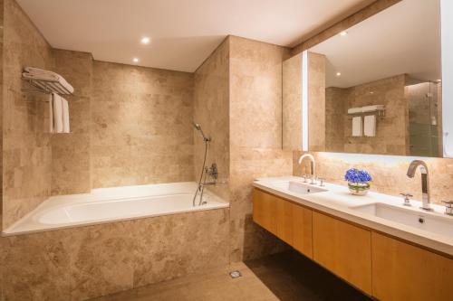 uma casa de banho com uma banheira e um lavatório e uma banheira em Ascott Raffles City Beijing em Pequim