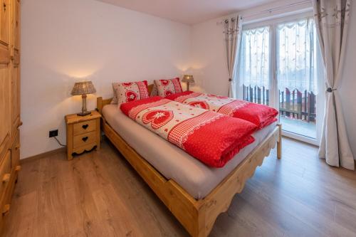 a bedroom with a bed with red sheets and a window at Touring Chez Georges in Grächen