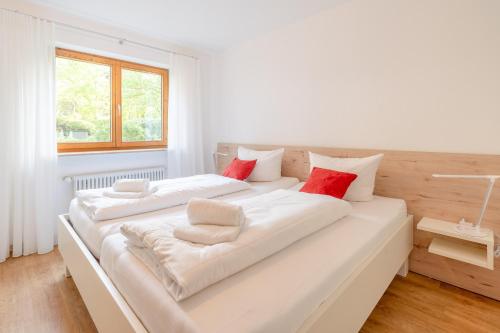 Duas camas num quarto branco com almofadas vermelhas em Bergsonne em Bad Hindelang
