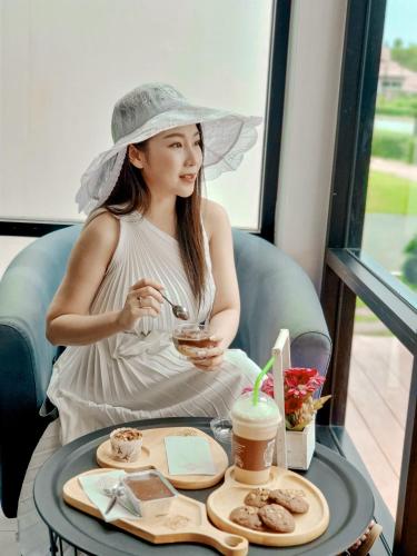 a woman in a hat sitting at a table with a drink at Saint Tropez Resort in Chao Lao Beach