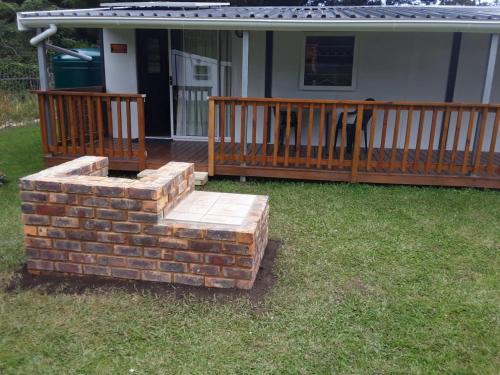 a brick fire pit on a porch with a deck at Nadine's Self-Catering Accommodation in Stormsrivier