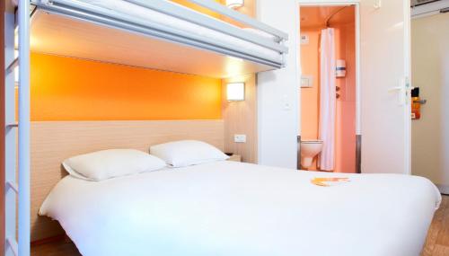 a bedroom with a large white bed and an orange wall at Premiere Classe Villepinte Centre - Parc des Expositions in Villepinte