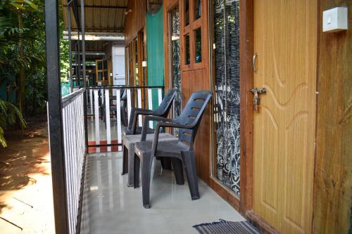 uma fila de cadeiras sentadas num alpendre em Palolem Cottages em Palolem