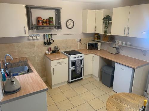 a kitchen with white cabinets and a stove top oven at Laura Ashley cosy inner terrace in Barnsley