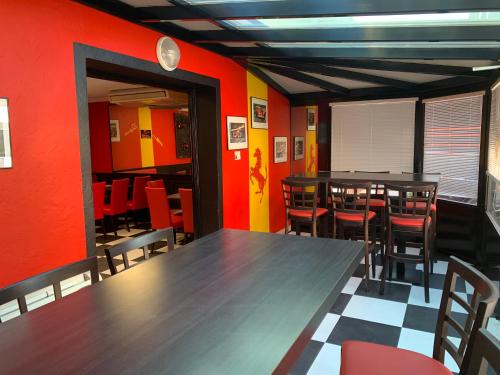 a dining room with tables and chairs and red walls at hôtel Le Cosy in Pont-de-Chéruy