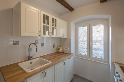 uma cozinha com armários brancos, um lavatório e uma janela em Apartments Bepi Komiza em Komiža