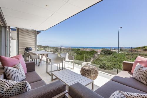 eine Außenterrasse mit Sofas, einem Tisch und Stühlen in der Unterkunft Smiths Beach Resort in Yallingup