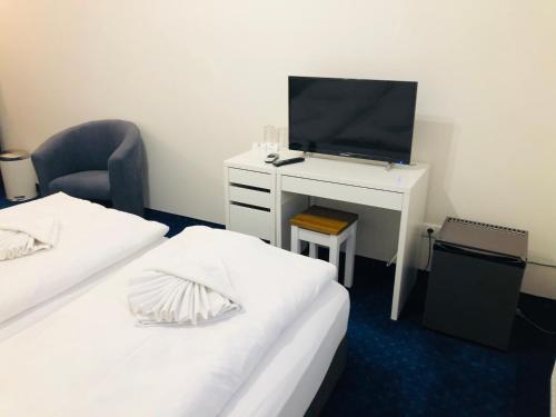 a room with two beds and a desk with a television at Penzión Pohoda in Nové Zámky
