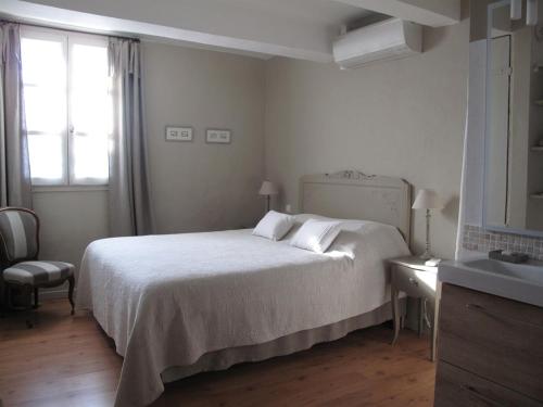 a white bedroom with a bed and a window at Le Mas de l'Olivier in Loriol-du-Comtat