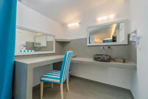 a bathroom with a blue chair and a sink at Central Fira Suites in Fira