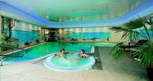zwei Frauen in einem Schwimmbad in einem Gebäude in der Unterkunft AKZENT Waldhotel Spa Rügen in Göhren
