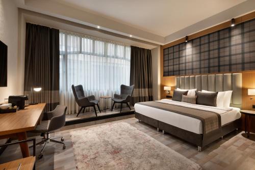 a hotel room with a bed and a desk and chairs at Ramada by Wyndham Budapest City Center in Budapest