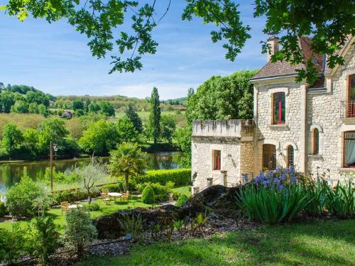 een oud stenen huis met een tuin en een meer bij manoir de la malartrie in Vézac