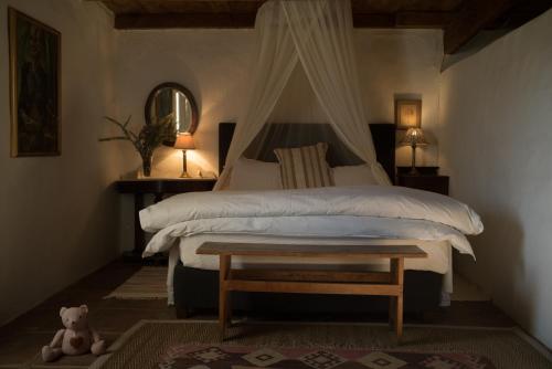 um quarto com uma cama e um ursinho de peluche em The Whitehouse em Barrydale