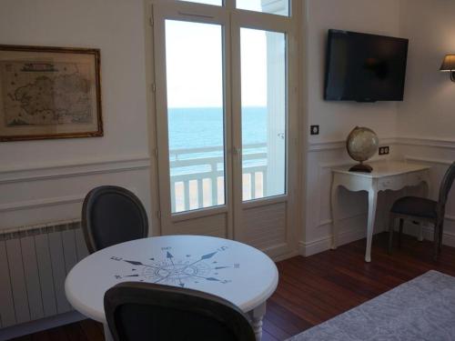ディナールにあるVilla Ker Eole Vue Merのテーブルと椅子、窓が備わる客室です。