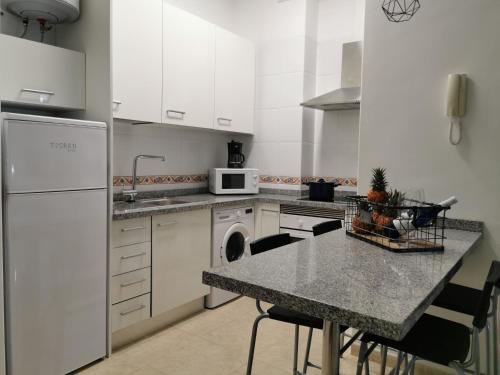 una cocina con electrodomésticos blancos y una mesa con sillas. en 23 DE ENERO en La Restinga