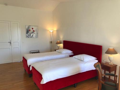 two beds in a hotel room with a red headboard at Le Jardin d'Homps in Homps
