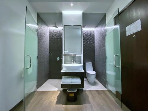 a bathroom with a sink and a toilet and a mirror at Bliss Hotel Singapore in Singapore