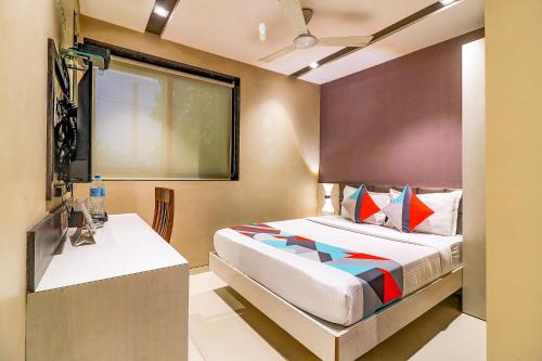 a bedroom with a bed and a table and a window at FabHotel Grand Heritage Kurla West in Mumbai
