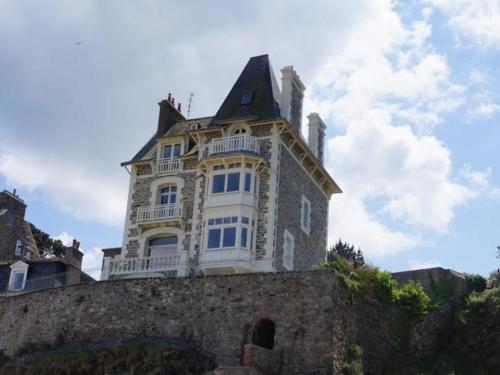 una casa grande en la parte superior de una pared de piedra en Villa XIXe Vue mer, en Dinard