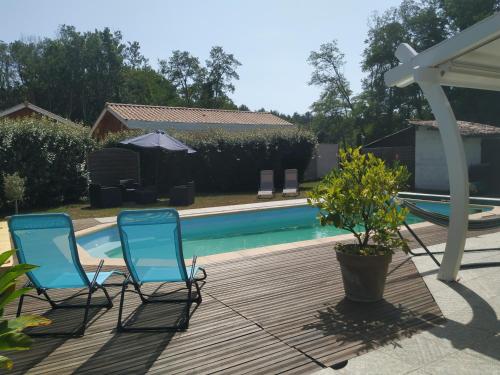 two blue chairs sitting next to a swimming pool at La résiniere de pirique in Parentis-en-Born