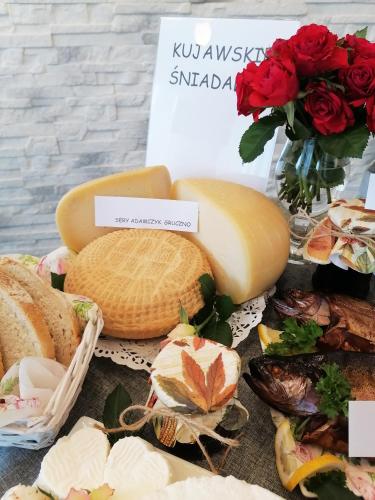 a table with cheese and bread and a vase of roses at Willa Lawenda in Ciechocinek